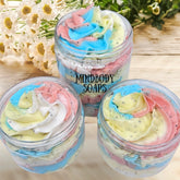 Body butter sugar scrub with colorful swirls, clear jars, and Mindbody Soaps text