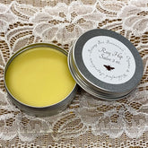 Rose Hip Salve in silver tin, yellow salve, Botany Bee Botanicals label on lid, lace background