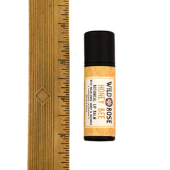 Lip balm tube with black cap, yellow label, and Wild Rose text visible
