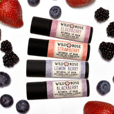 Lip balm gift set with black tubes, berry labels, and fruit on white background