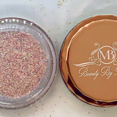 Side view of iridescent pink fairy dust glitter eyeshadow pot catching light with sparkling particles