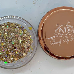 Glitter in clear jar with gold and iridescent flecks, next to Beauty By MB rose gold lid