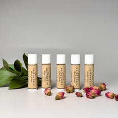 Lip balm tubes with white caps and brown labels, Adirondack Natural Skincare brand, with rose buds