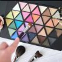 Eyeshadow palette with colorful triangular shades and makeup brushes on white surface