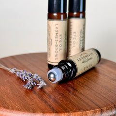 Eye oil bottles with brown glass, black caps, and silver rollerball applicator, with lavender