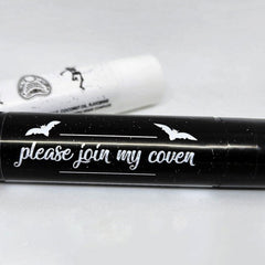 Black lipstick tube with white bat illustrations and text "please join my coven" on black background