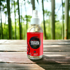 Facial toner bottle with red label, clear glass, white spray top, on wood surface