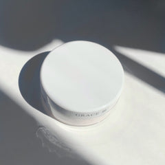 White cosmetic jar with "GRACE" label, round shape, and shadow pattern