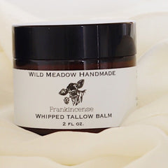 Close-up of rich whipped tallow balm in a sleek jar with golden lid, showcasing creamy texture