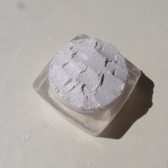 Close-up of loose shimmering white mineral eyeshadow powder with fine sparkles, vegan formula in open jar