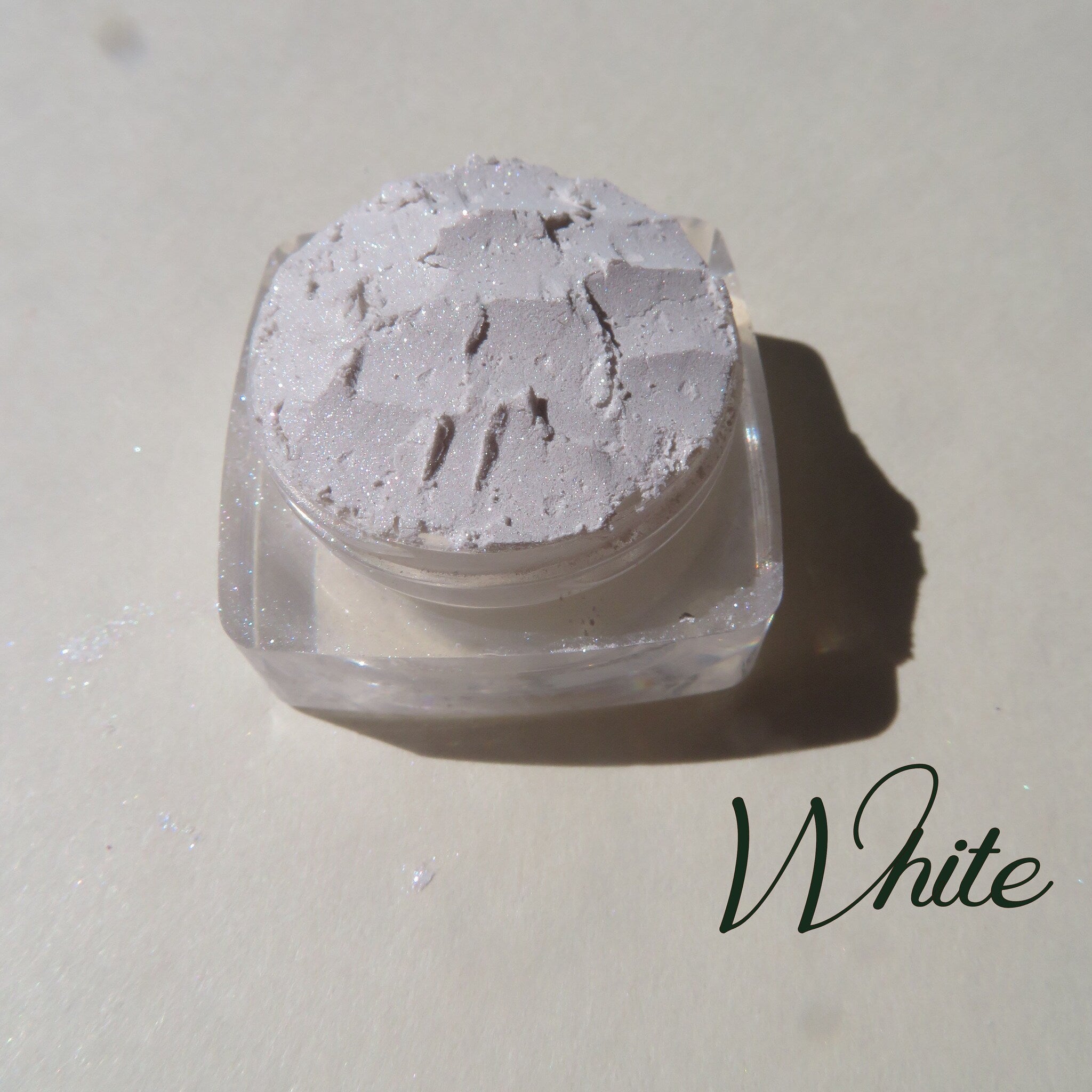 Soft white loose mineral eyeshadow with shimmer in a round compact, vegan highlighter base for subtle glow