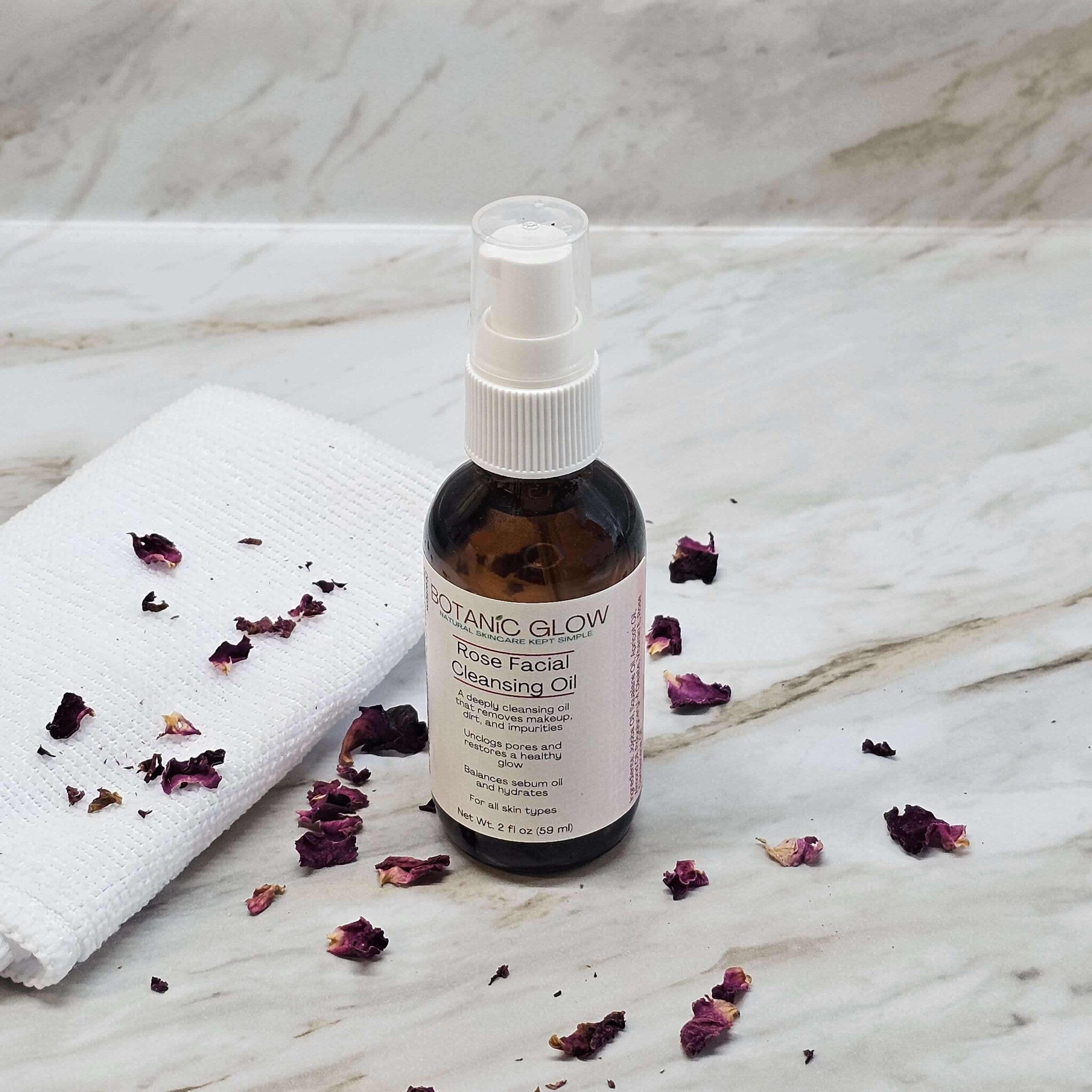 Facial Cleansing Oil bottle with white pump, brown glass, and Botanic Glow label, with rose petals