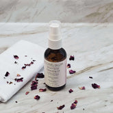 Facial Cleansing Oil bottle with white pump, brown glass, and Botanic Glow label, with rose petals