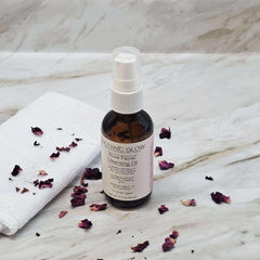 Facial Cleansing Oil bottle with white pump, brown glass, and Botanic Glow label, with rose petals