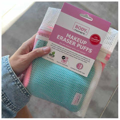 Makeup Eraser Puffs, pink and teal mesh cloths with white wash bag, held in hand with Body Moment packaging