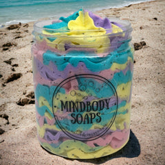 Mindbody Soaps jar of colorful soap, pastel swirls, clear plastic container, on sandy beach