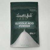 Glycolic acid powder in a dark green bag with white powder and Huetiful Labs text visible