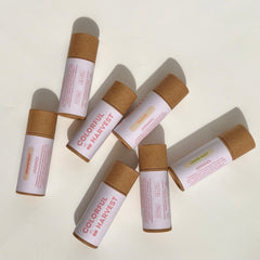 Lip balm tubes in brown and white with Colorful Harvest text, arranged on white surface