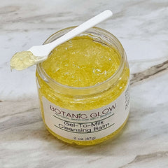 Gel to milk cleansing balm in yellow, clear jar with white spoon, Botanic Glow label visible