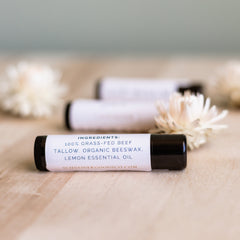 Lip balm tubes with black caps and white labels on a wooden surface, Schneider Goods Co