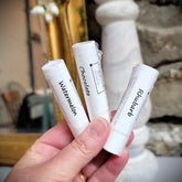 Lip balm tubes white with flavor labels, held in hand, KraftyChickStudios brand visible