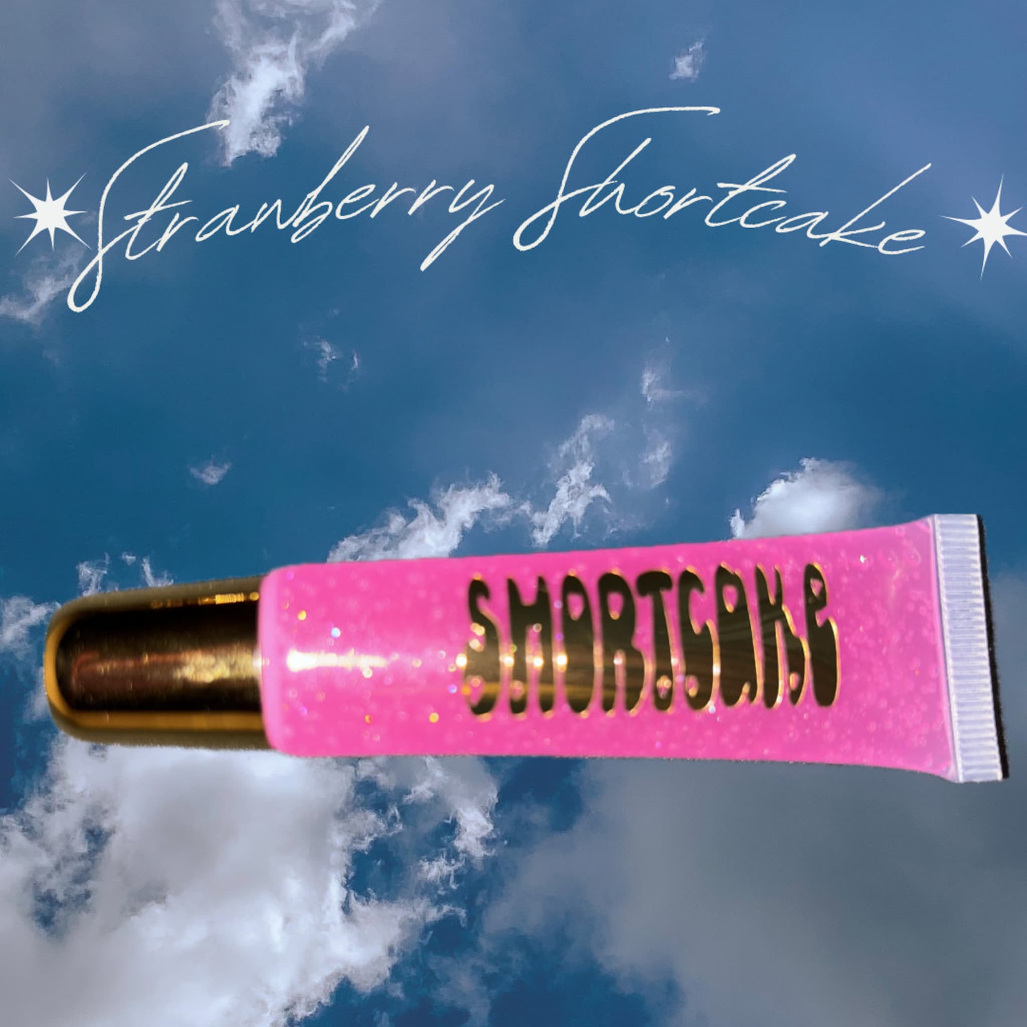 Lip gloss tube with pink glitter, gold cap, and "Strawberry Shortcake" text
