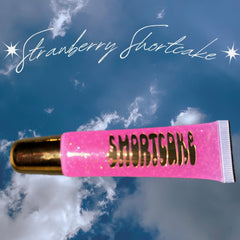 Lip gloss tube with pink glitter, gold cap, and "Strawberry Shortcake" text