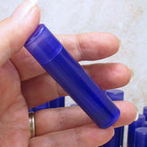 Lip gloss tube, dark purple translucent plastic, held in hand
