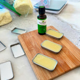 Lip balm tins with yellow balm on a wooden board, Plant Therapy essential oil bottle