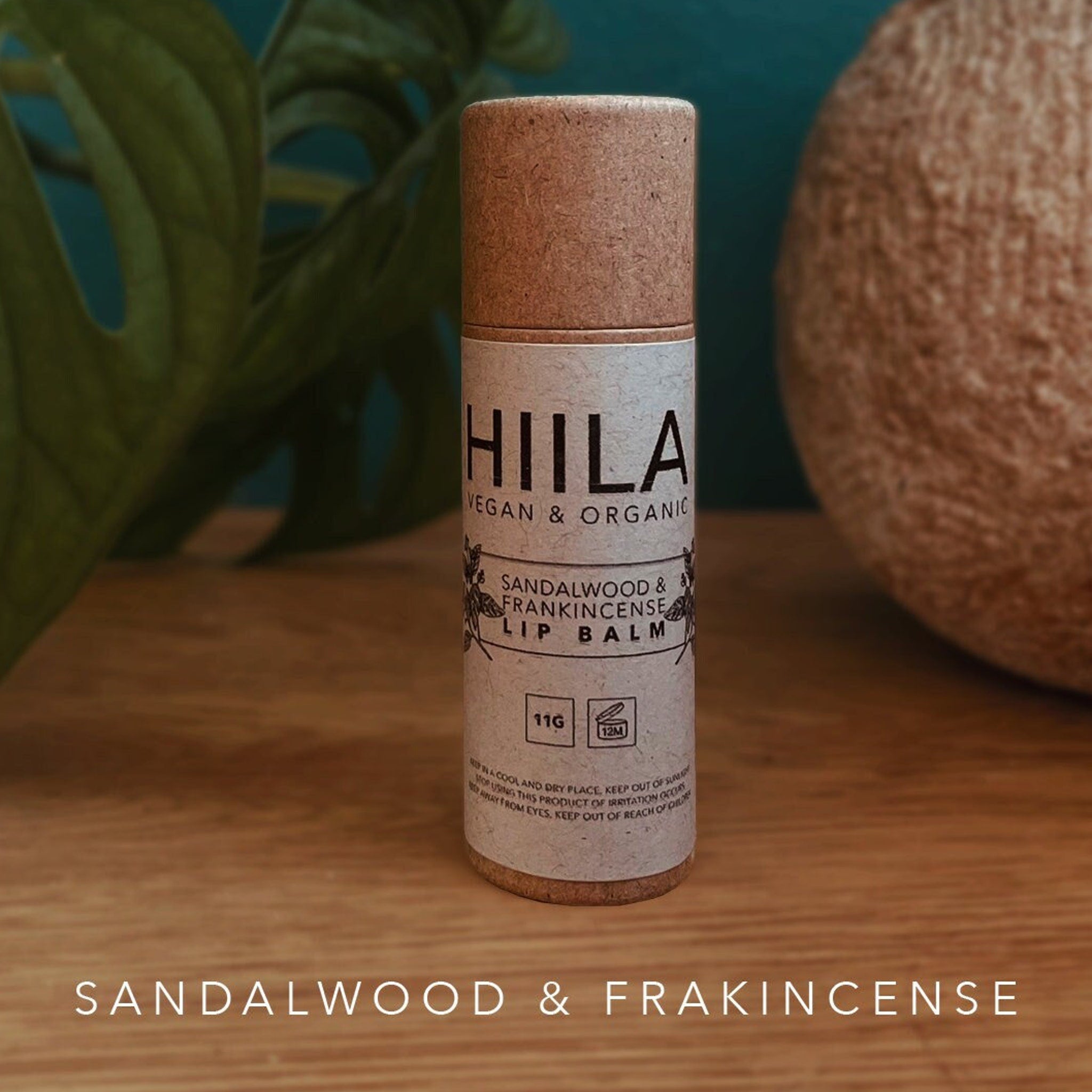 Lip balm tube with brown cap and HIILA label, on wooden surface