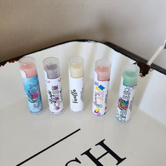 Lip balm tubes with clear caps, colorful labels, and BEEzy & Birch text on white surface