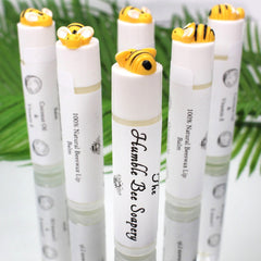 Lip balm tubes with yellow bee toppers, white labels, and The Humble Bee Soapery text