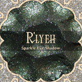 Eye shadow with dark green and pink sparkle, R'LYEH brand name, decorative border around the product