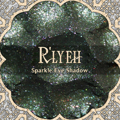 Eye shadow with dark green and pink sparkle, R'LYEH brand name, decorative border around the product