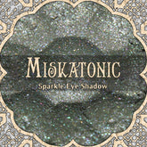Eye makeup shimmer shadow, grey with sparkle, MISKATONIC brand name visible in ornate frame
