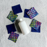 Makeup remover pads, navy blue and geometric patterned fabric pads, with a white bottle on a towel