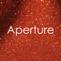 Small glass jar with gold sifter lid containing vibrant glitter eye shadow in assorted colors