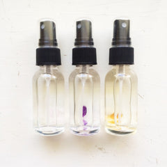 Toner spray bottles with clear glass, black caps, and crystals inside
