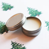 Lip balm in silver metal tin with white balm, lid off, on patterned surface