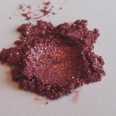 Eye shadow, burgundy mineral powder with glitter, close-up view on white surface