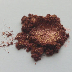 Eyeshadow powder, dark brown with gold shimmer and glitter, close-up view