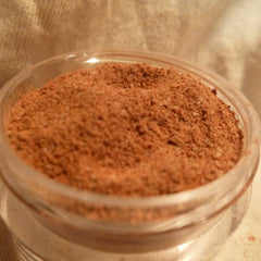 Powdered spice, brown granules in a clear glass container, close-up view