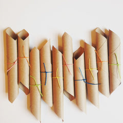 Cardboard tubes with colorful string ties, brown paper material, arranged in a row