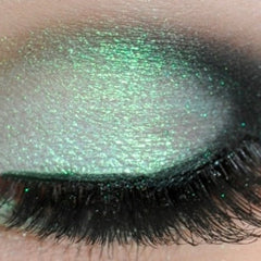 Eyeshadow with green shimmer, dark eyeliner, and black eyelashes on eye