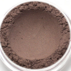 Brown eyeshadow powder with textured edges and smooth center in a clear container