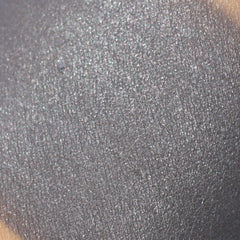 Gray eyeshadow swatch with glitter, textured finish, and skin visible
