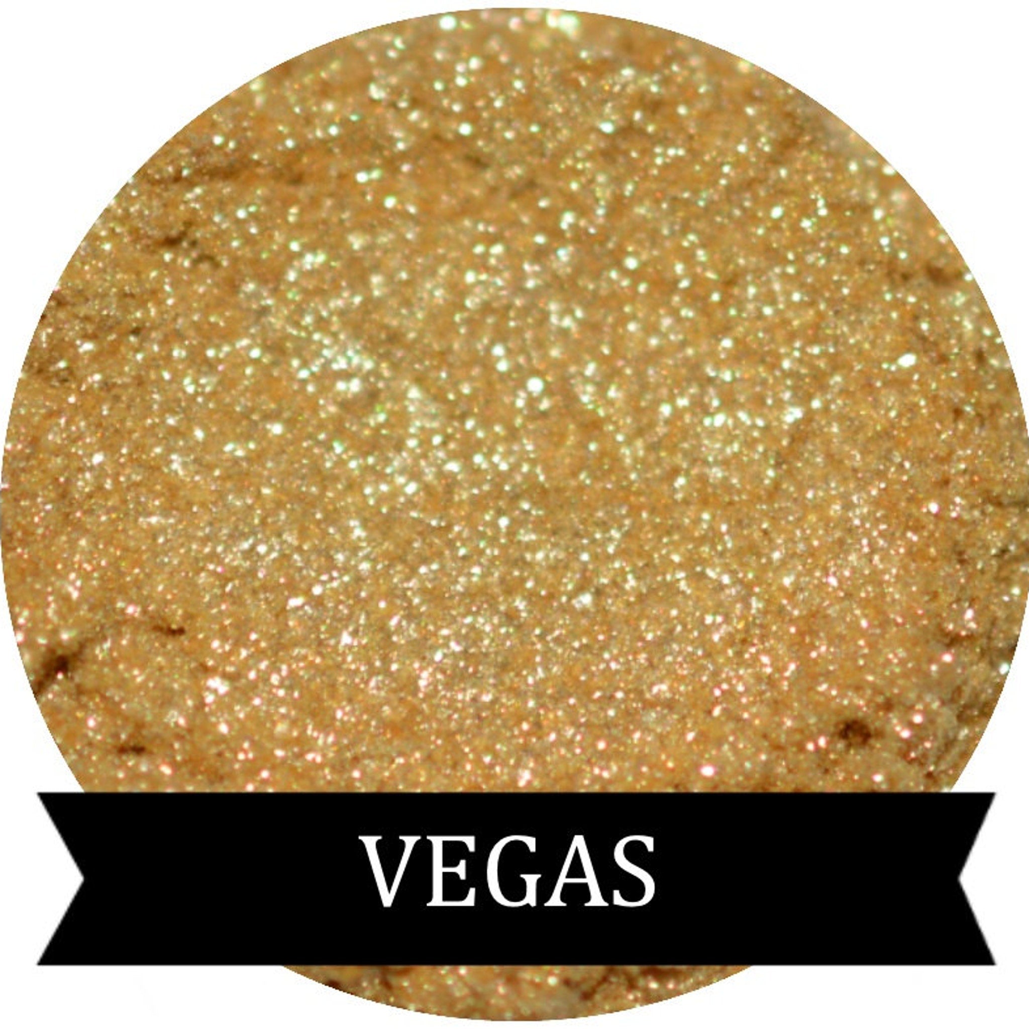 Close-up of sparkling gold eye shadow in a round compact with reflective surface and shimmer particles