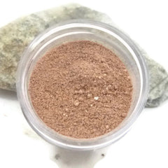Adzuki facial scrub in clear plastic container, light brown powder, and grey rock background