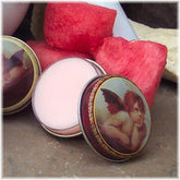 Watermelon lip balm in a tin, open, with a cherub design and pink balm visible