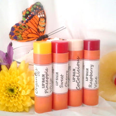 Lip balm tubes with yellow, red, and white labels, orange base, and colorful butterfly in background